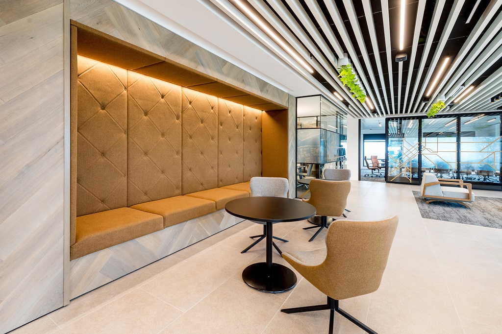 Tufted banquette breakout under linear slat ceiling — commercial interior design by Ab & Zen Interior