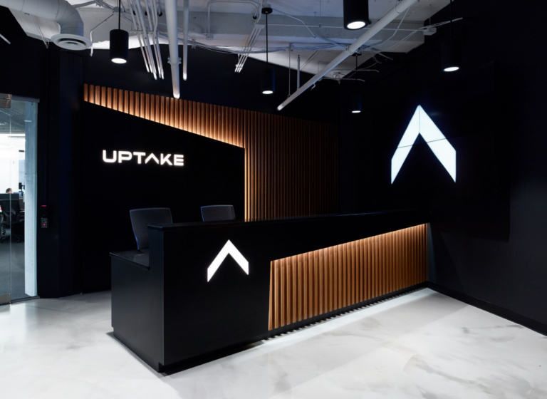 Dark-tone reception with backlit signage & timber fins — commercial interior design by Ab & Zen Interior